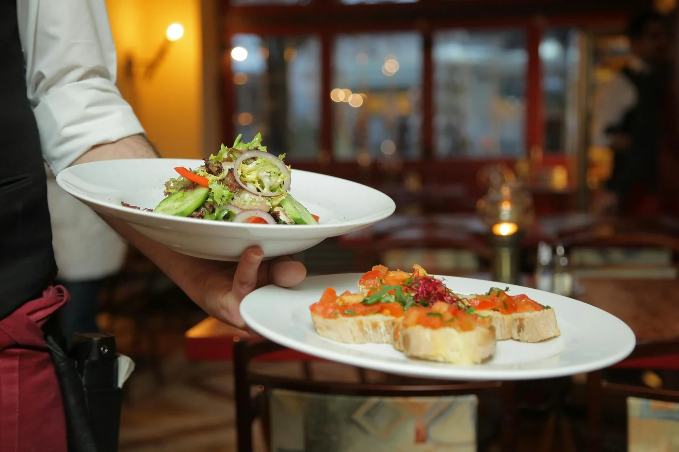 Terasa restaurace u moře za soumraku, na stole meze a grilovaná ryba.